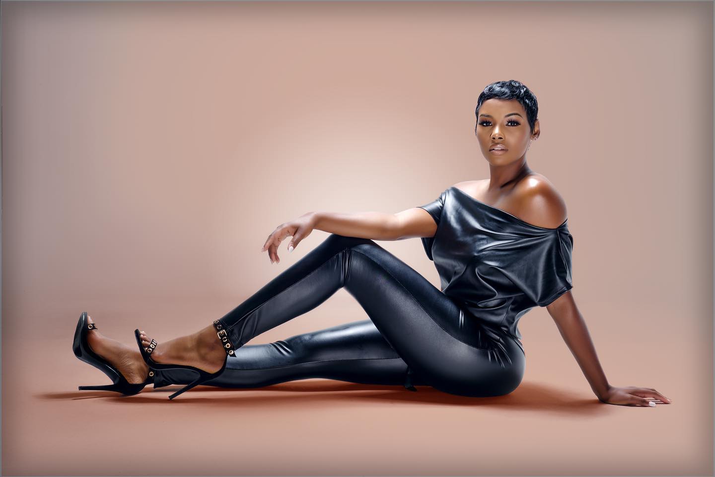 Studio portrait photographer Jacksonville FL — black leather off-shoulder set seated warm neutral background by HiDef Pixel